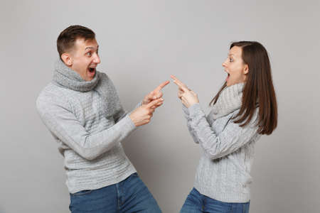 Young cute couple girl guy in gray sweaters, scarves together isolated on grey wall background,...
