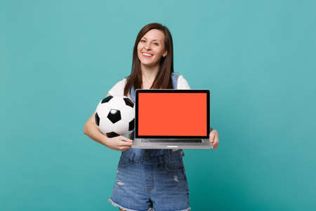 Beautiful woman football fan hold soccer ball laptop pc computer with blank empty screen isolated on blue turquoise wall background. People emotions, sport family leisure concept. Mock up copy spaceの写真素材
