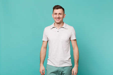 Portrait of attractive young man in casual clothes standing isolated on blue turquoise wall background in studio. People sincere emotions, lifestyle concept. Mock up copy space. Advertising areaの写真素材