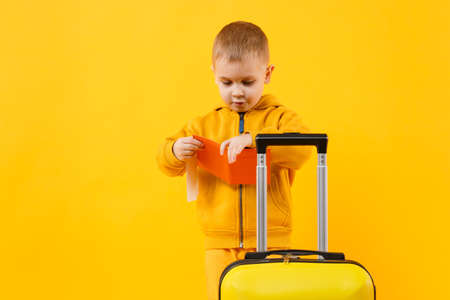 Little traveler tourist kid boy 3-4 years old isolated on yellow orange wall background studio. Passenger traveling abroad to travel on weekends getaway. Air flight journey concept. Mockup copy spaceの写真素材