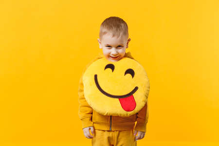 Little cute kid boy 3-4 years old wearing yellow clothes isolated on bright orange wall background,...