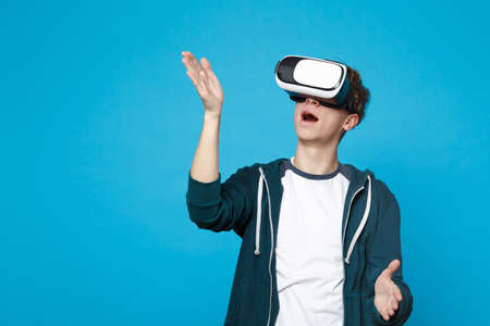 Amazed young man in headset touch something like push click on button, pointing at floating virtual...