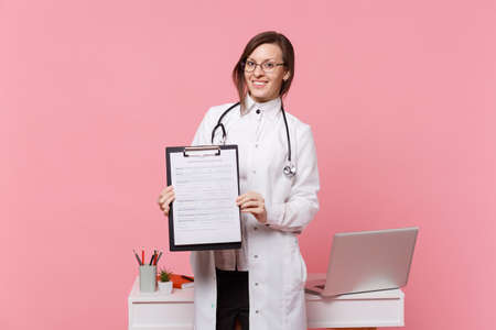 Cute female doctor stand in front of desk with pc computer, medical document in hospital isolated on...