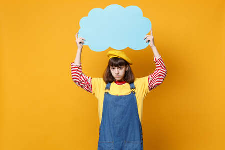 Upset puzzled girl teenager in french beret, denim sundress hold blue empty blank Say cloud, speech...