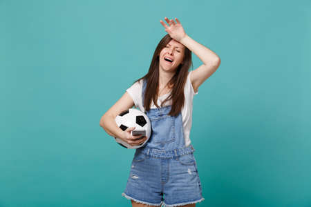 Crying aggrieved woman football fan holding soccer ball, mobile phone and putting hand on head...