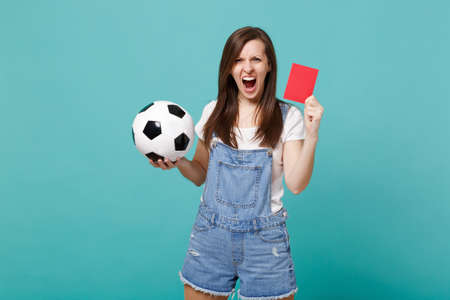 Screaming angry young woman football fan support team with soccer ball, red card, propose player retire from field isolated on blue turquoise background. People emotions, sport family leisure conceptの写真素材
