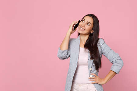 Pretty young woman in striped jacket talking on mobile phone, conducting pleasant conversation...