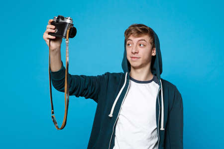 Portrait of handsome young man in casual clothes doing selfie shot on retro vintage photo camera...