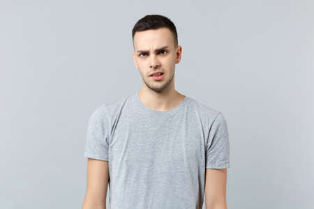 Portrait of perplexed concerned young man in casual clothes standing and looking camera isolated on...