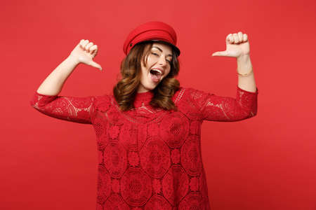 Portrait of cheerful confident young woman in lace dress cap pointing thumbs on herself isolated on...