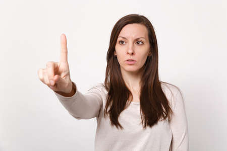 Serious young woman touch something like push click on button pointing at floating virtual screen...