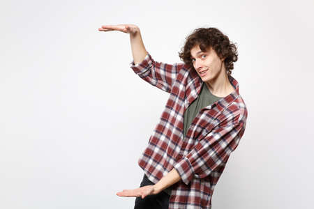 Portrait of handsome young man in casual clothes gesturing demonstrating size with vertical workspace isolated on white wall background. People sincere emotions, lifestyle concept. Mock up copy spaceの写真素材