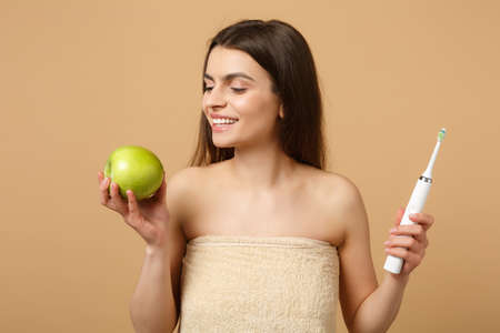 Close up brunette half naked woman 20s with perfect skin, nude make up hold brush isolated on beige...