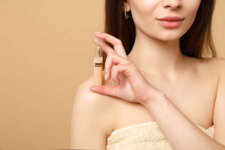 Close up brunette half naked woman 20s with perfect skin, nude make up isolated on beige pastel wall...