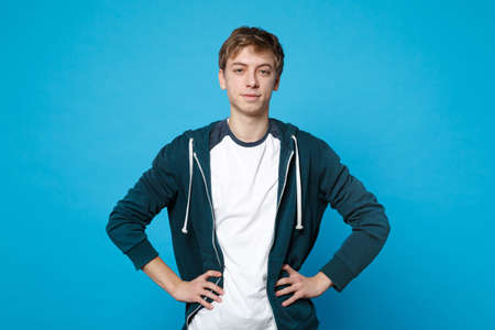 Portrait of attractive young man in casual clothes standing with arms akimbo on waist isolated on...