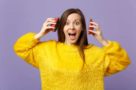 Amazed young woman keeping mouth wide open, holding halfs of pitahaya, dragon fruit near ears isolated on violet pastel background. People vivid lifestyle relax vacation concept. Mock up copy spaceの写真素材
