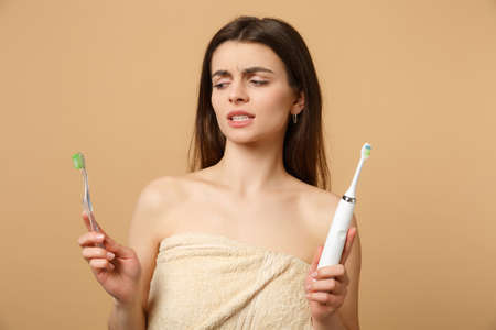 Close up brunette half naked woman 20s perfect skin nude make up hold brushes isolated on beige pastel wall background studio portrait. Health care cosmetic procedures concept. Mock up copy spaceの写真素材
