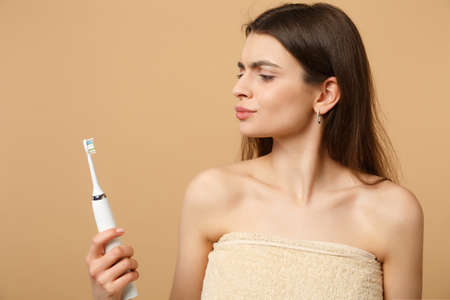 Close up brunette half naked woman 20s with perfect skin, nude make up hold brush isolated on beige pastel wall background studio portrait. Health care cosmetic procedures concept. Mock up copy spaceの写真素材