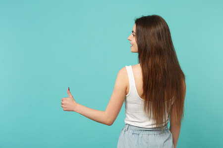 Back rear view of young woman in light casual clothes looking aside, showing thumb up isolated on...