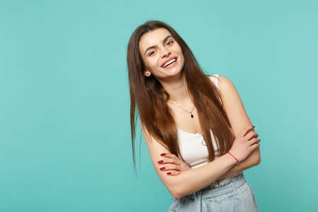 Portrait of cheerful young woman in light casual clothes looking camera holding hands crossed...
