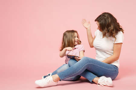 Woman in light clothes have fun with cute child baby girl. Mother, little kid daughter isolated on...