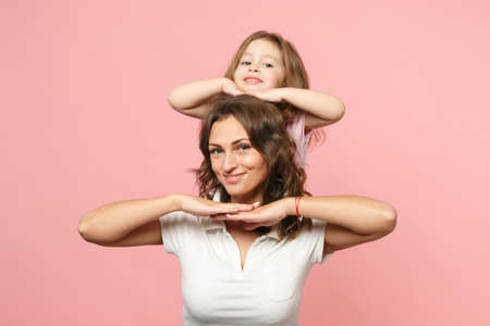 Woman in light clothes have fun with cute child baby girl. Mother, little kid daughter isolated on pastel pink wall background, studio portrait. Mother's Day love family, parenthood childhood conceptの写真素材