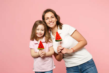Woman in light clothes have fun with cute child baby girl. Mother, little kid daughter isolated on pastel pink wall background, studio portrait. Mother's Day love family, parenthood childhood conceptの写真素材