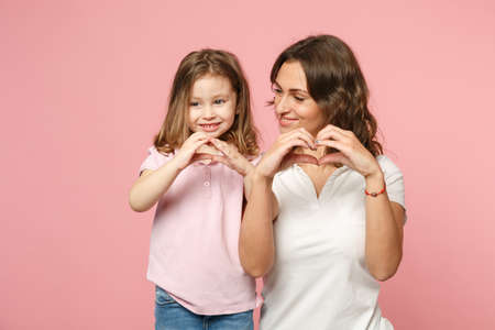 Woman in light clothes have fun with cute child baby girl. Mother, little kid daughter isolated on pastel pink wall background, studio portrait. Mother's Day love family, parenthood childhood conceptの写真素材