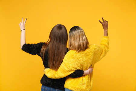 Back view women friends european and african american in black yellow clothes standing posing...