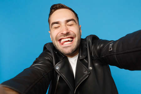 Close up selfie of stylish young unshaven man in black leather jacket white t-shirt looking camera...