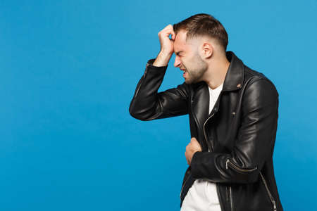 Young sad frustrated worried unshaven man in black jacket white t-shirt put arm on head isolated on...