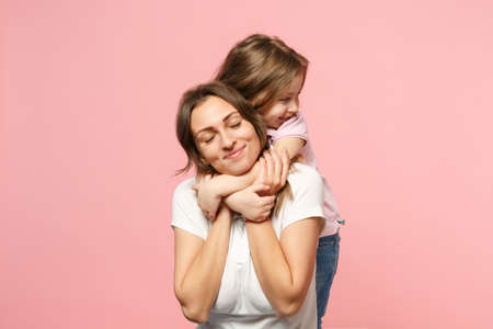 Woman in light clothes have fun with cute child baby girl. Mother, little kid daughter isolated on pastel pink wall background, studio portrait. Mother's Day love family, parenthood childhood conceptの写真素材