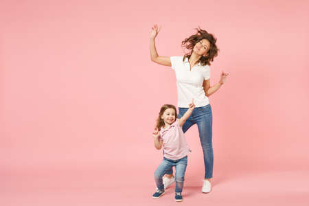 Woman in light clothes have fun with cute child baby girl. Mother, little kid daughter isolated on pastel pink wall background, studio portrait. Mother's Day love family, parenthood childhood conceptの写真素材