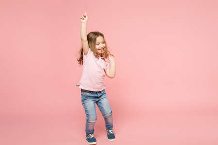 Little cute child kid baby girl 3-4 years old wearing light clothes dancing isolated on pastel pink wall background, children studio portrait. Mother's Day, love family, parenthood childhood conceptの写真素材