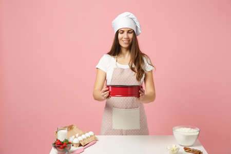 Chef cook confectioner or baker in apron white t-shirt, toque chefs hat cooking cake or cupcake at...