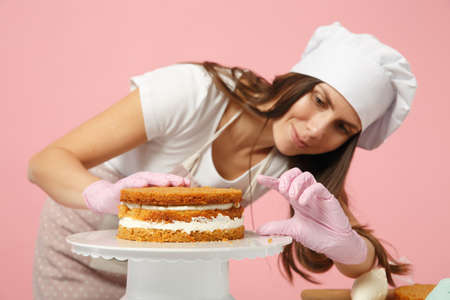 Chef cook confectioner or baker in white t-shirt, toque chefs hat cooking at table isolated on pink...