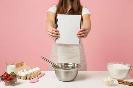 Close up housewife chef cook confectioner or baker in white t-shirt toque chefs hat hold notebook...