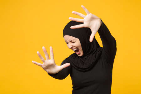 Sad upset crying confused young arabian muslim woman in hijab black clothes posing isolated on...