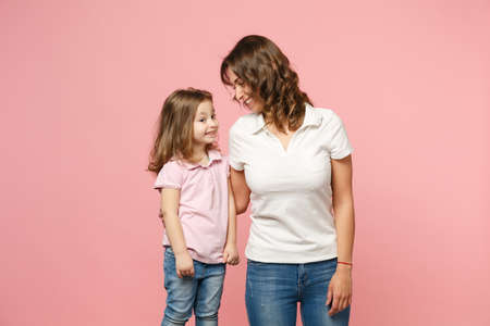 Woman in light clothes have fun with cute child baby girl. Mother, little kid daughter isolated on pastel pink wall background, studio portrait. Mother's Day love family, parenthood childhood conceptの写真素材