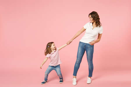 Woman in light clothes have fun with cute child baby girl. Mother, little kid daughter isolated on pastel pink wall background, studio portrait. Mother's Day love family, parenthood childhood conceptの写真素材