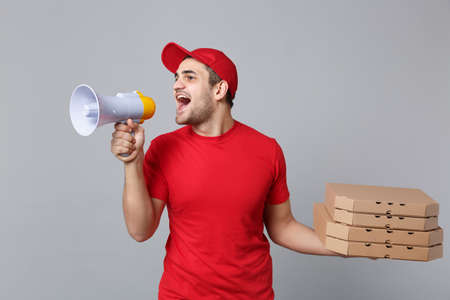 Delivery man giving hold food order pizza boxes isolated on grey background. Professional male...
