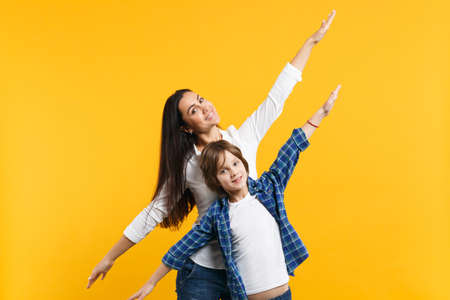 Cheerful woman in casual clothes have fun with child boy. Mother, little kid son spreading hands...