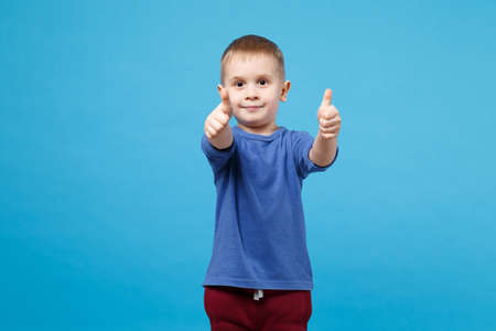 Smiling fun kid boy 4 years old wearing blue t-shirt clothes showing thumb up gesture isolated on...