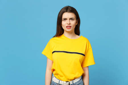 Portrait of perplexed bewildered concerned young woman in vivid casual clothes standing, looking...