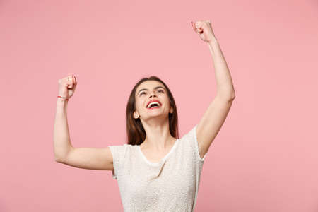 Happy young woman in casual light clothes posing isolated on pastel pink background studio portrait....