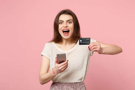 Excited young woman in casual light clothes posing isolated on pastel pink background. People...