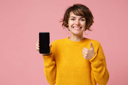Funny young brunette woman girl in yellow sweater posing isolated on pastel pink background. People...