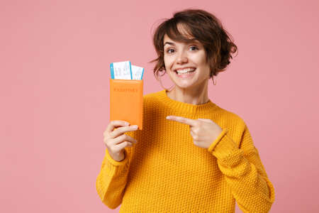 Smiling young brunette woman girl in yellow sweater posing isolated on pastel pink wall background....