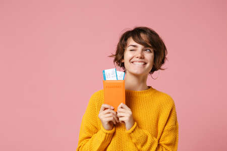 Pensive funny young brunette woman girl in yellow sweater posing isolated on pastel pink wall...