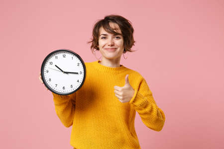 Smiling young brunette woman girl in yellow sweater posing isolated on pastel pink background in...